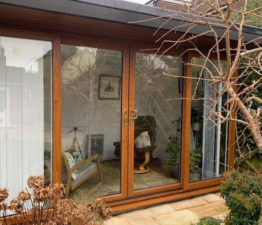 The external view of a therapy room, with glass doors, two chairs and a patio area outside.