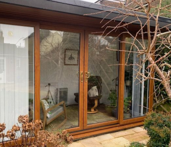The external view of a therapy room, with glass doors, two chairs and a patio area outside.